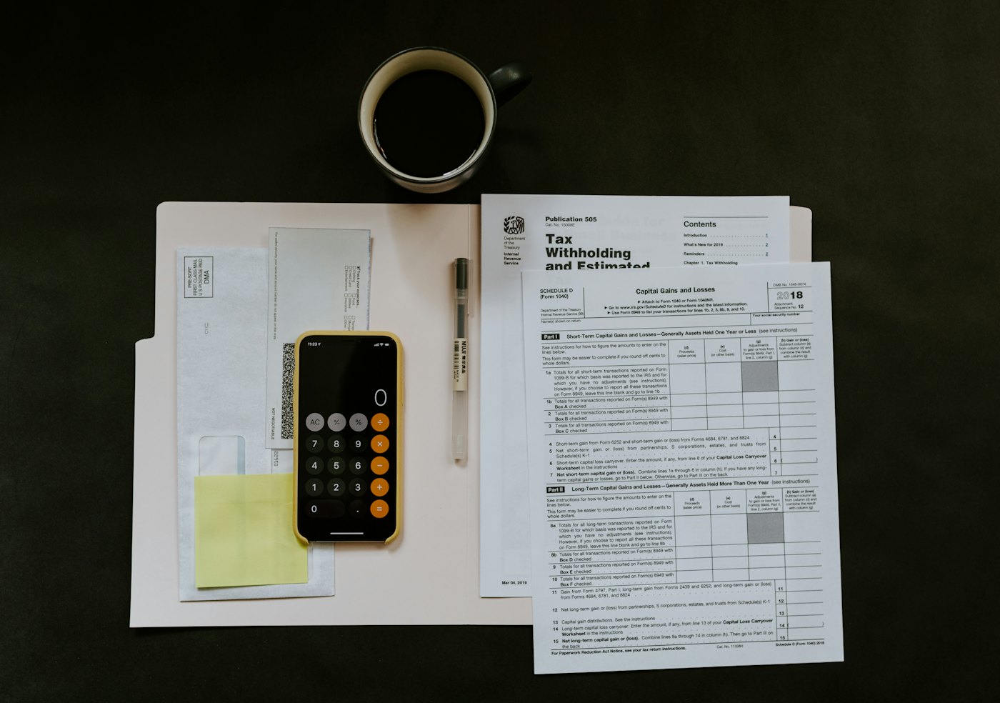 Financial forms and a calculator laid out on a dark desk