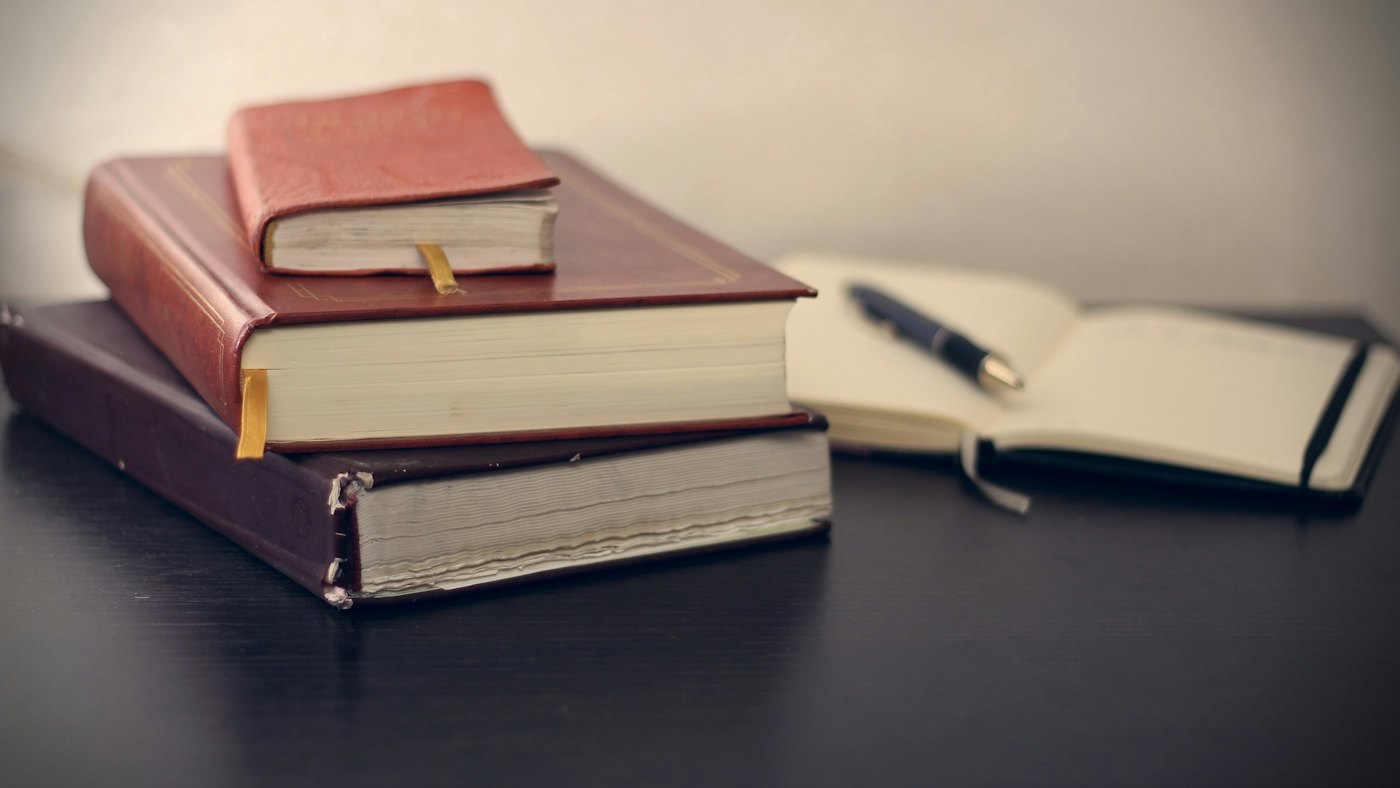Stacked legal volumes beside an open notebook and pen