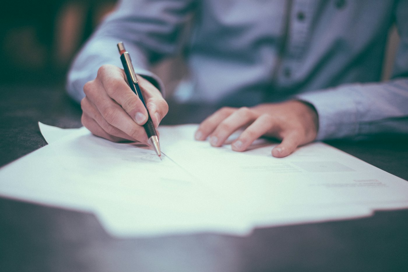 Person signing legal paperwork at a desk